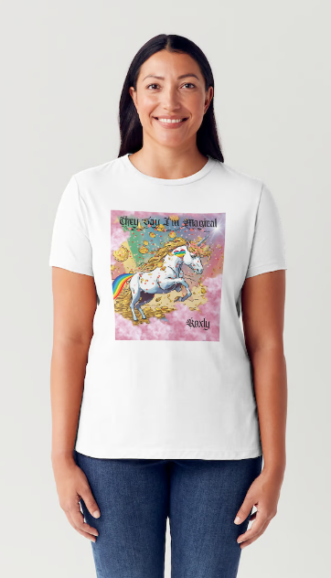 This is a black t-shirt entitled "they say I'm magical", features a White unicorn with a blinding light from its' horn, a golden mane and a rainbow tail galloping through cotton candy pink clouds filled with raining golden coins and a multicolor background. This shirt is for the bold unapologetically yourself type. YOLO. This is part of the Mike Roxly Collection.