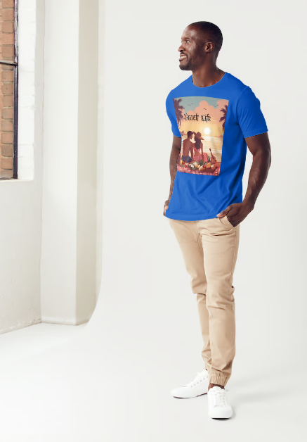 This is a model wearing a t-shirt entitled "Beach Life" men's graphic t-shirt. The shirt itself is blue in color. Made of soft and breathable cotton, this shirt embodies the perfect beach day with a romantic scene full of warm colors, it features a couple enjoying a sunset picnic surrounded by palm trees by the ocean. Let the bold design and adventurous spirit inspire your next adventure!" This is a Mike Roxly collection T-shirt